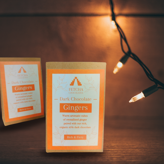 Image shows Fetcha Chocolates handmade dark chocolate gingers,  which are vegan, dairy free, gluten free come in plastic-free packaging. The packaging is brown kraft cardboard with an orange label.