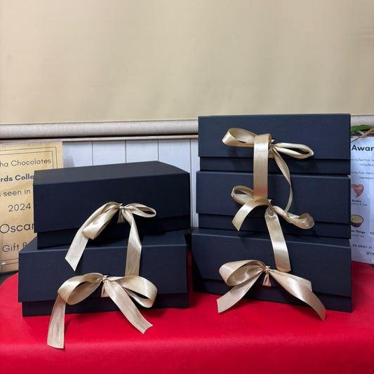 Set of black gift boxes with ribbons on a red table.