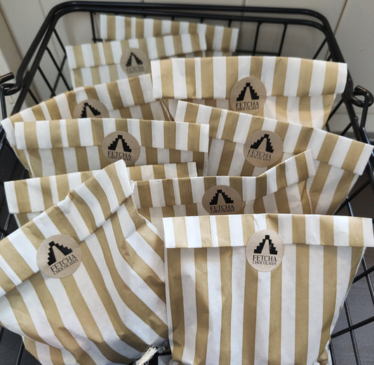 Image shows a basket full of striped paper bags full of vegan and gluten free pick n mix, being sold by Fetcha Chocolates