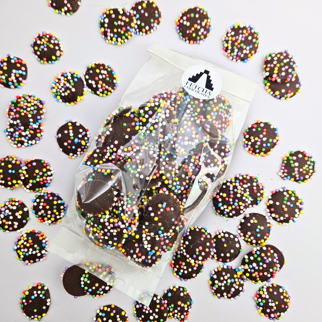Bag of vegan chocolate jazzies with colourful sprinkles on a white background