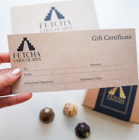 Image shows a hand holding a card gift certificate valid for shopping on Fetcha Chocolates online and in person in the Fetcha Chocolates shop